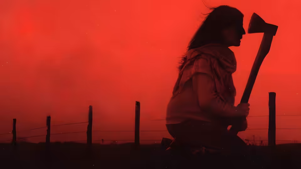 A kneeling figure grips an axe beside a fence under a red sky
