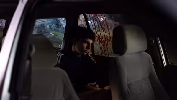 Santino (Marcelo Michinaux) sits alone in the back seat beside a blood-streaked window