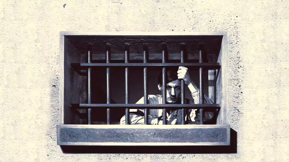 Fontaine peers through barred prison-cell window, raising a hand beside the iron bars