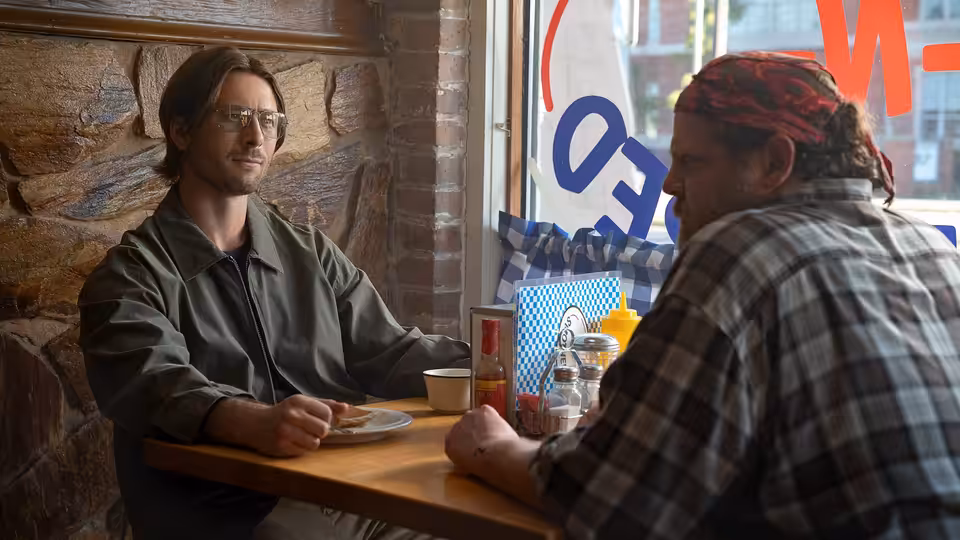 Gary Johnson (Glen Powell) sits across from a man at a diner table