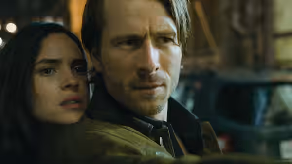 Madison Figueroa Masters (Adria Arjona) clings to Gary Johnson (Glen Powell) as they watch something offscreen
