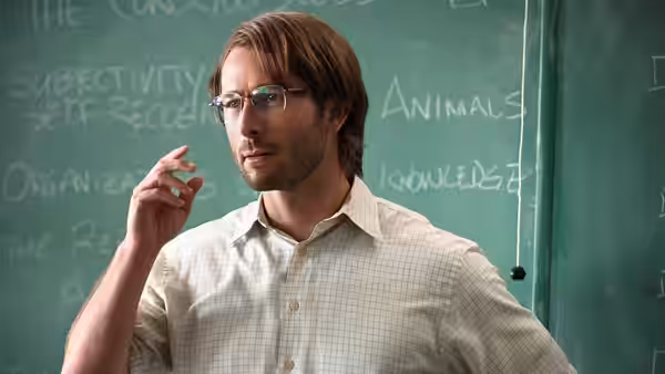 Gary Johnson (Glen Powell) gestures while teaching in front of a chalkboard