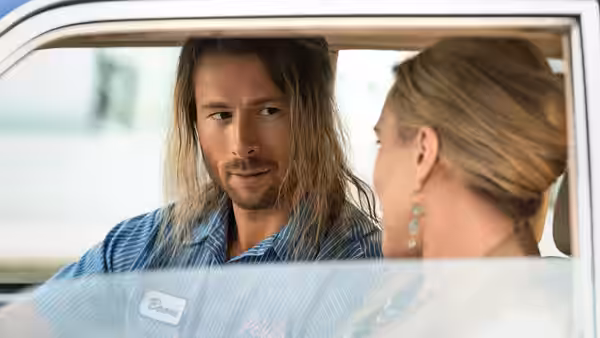 Gary Johnson (Glen Powell) talks with a woman through an open car window