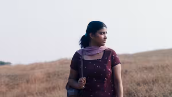 Parvaty (Chhaya Kadam) stands in a dry field, holding her bag strap