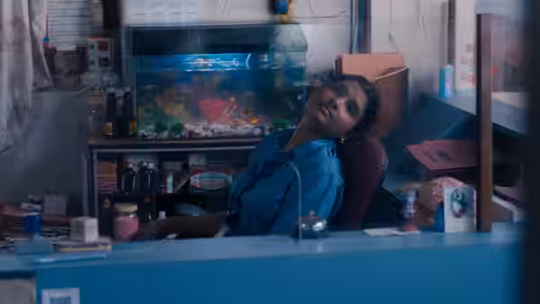 A nurse leans back behind a hospital reception desk beside a lit aquarium