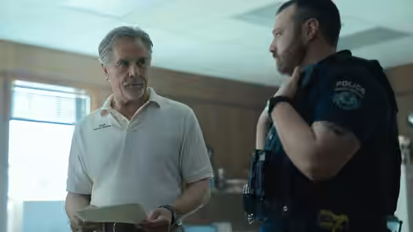Chief Sandy Burnne (Don Johnson) holds papers beside a uniformed police officer