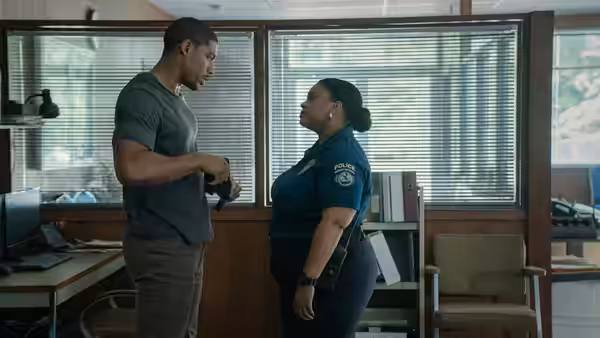 Terry Richmond (Aaron Pierre) speaks with a uniformed police officer in an office