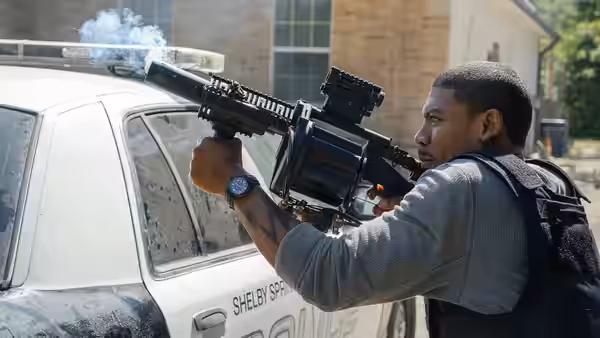 Terry Richmond (Aaron Pierre) aims a weapon at a marked police car
