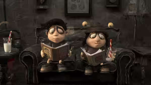 Two children read books together on a sofa