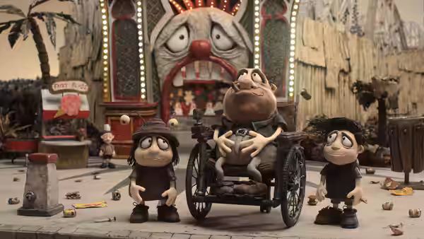 A man in a wheelchair sits between two children outside a carnival attraction