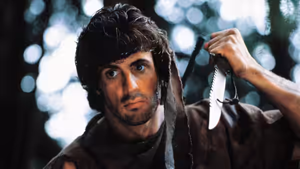 John Rambo (Sylvester Stallone) raises a knife in the forest