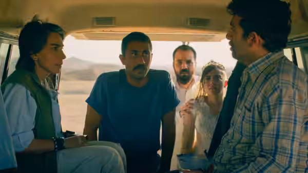 Five people confront a curly-haired man inside a van