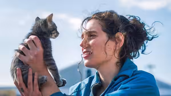Agnes (Eva Victor) smiles at a kitten she holds outdoors