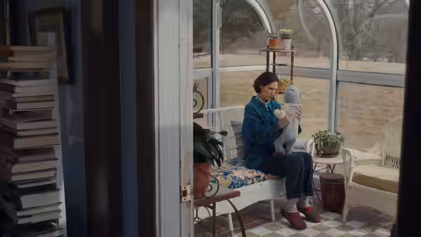 Agnes (Eva Victor) cradles a baby in a sunroom