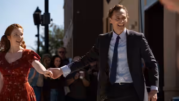 Chuck Krantz (Tom Hiddleston) walks hand in hand with a woman in a red dress