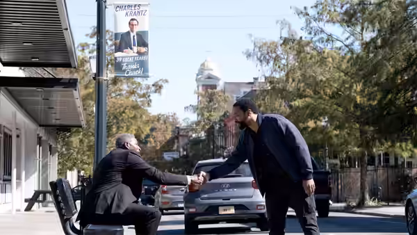 Marty Anderson (Chiwetel Ejiofor) shakes hands with a seated man on a town street