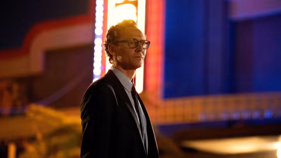 Chuck Krantz (Tom Hiddleston) stands before brightly lit theater signage