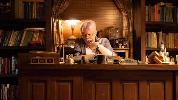 Albie Krantz (Mark Hamill) sits at his desk among books and papers