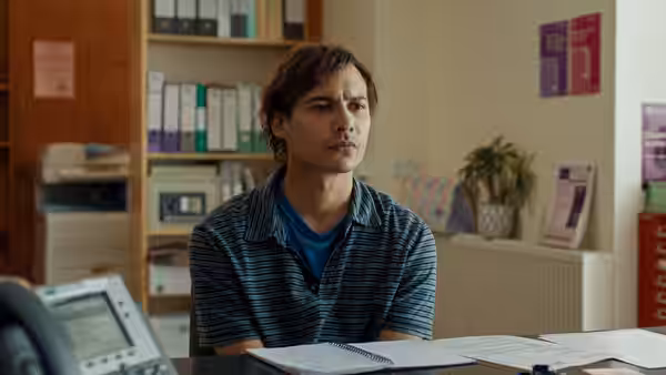 Mike (Frank Dillane) sits at a desk in an office