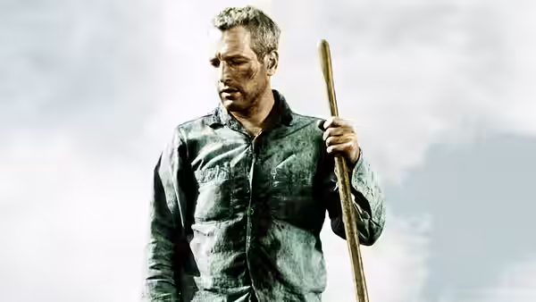 Luke Jackson (Paul Newman) holds a shovel and looks across the work camp