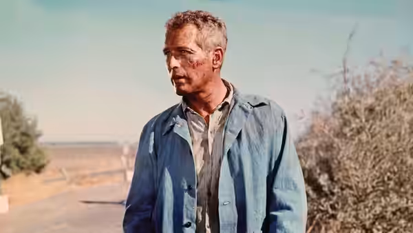 Luke Jackson (Paul Newman) stands outdoors in his prison work clothes