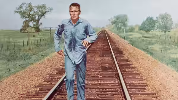 Luke Jackson (Paul Newman) walks along railway tracks in his prison work clothes