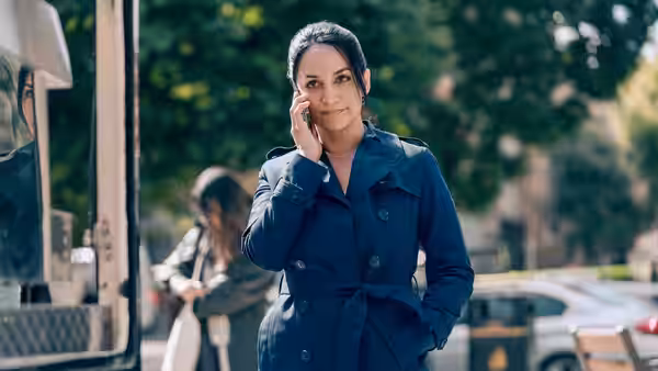Zahra Gahfoor (Archie Panjabi) speaks on her phone beside parked vehicles
