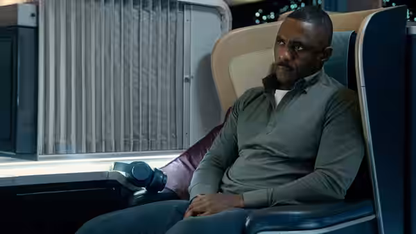 Sam Nelson (Idris Elba) sits alone in a passenger seat aboard the plane