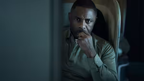 Sam Nelson (Idris Elba) sits pensively in his plane seat, hand against his mouth
