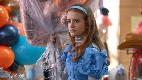 Jen (Mairéad Tyers) holds a cluster of balloons at a party