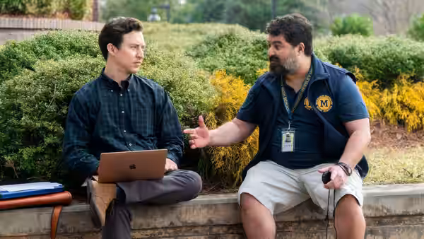 Evan Marquez (Brian Jordan Alvarez) sits with a laptop while Markie Hillridge (Sean Patton) gestures beside him
