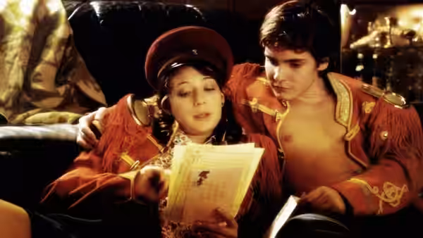 A man and woman in ornate red uniforms examining a document together