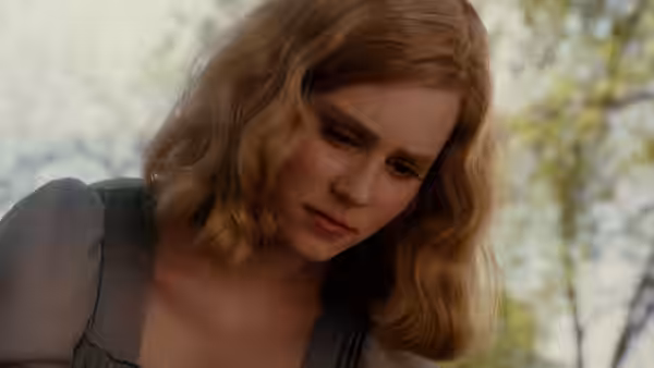 Young Sandra Bloom gazes downward with a somber expression outdoors
