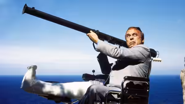 Roger Moore as Chief Inspector Jacques Clouseau aims a large gun from a boat at sea