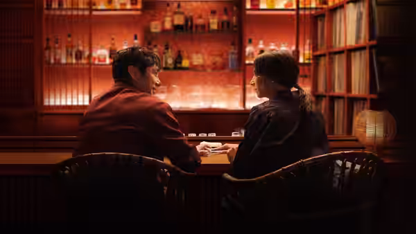 Suzie (Rashida Jones) and Masa sit together at a warmly lit bar