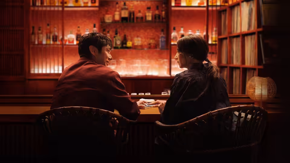 Suzie (Rashida Jones) and Masa sit together at a warmly lit bar