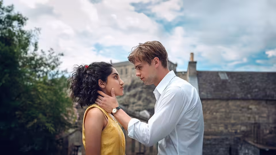 Emma (Ambika Mod) and Dexter (Leo Woodall) stand close together in a courtyard