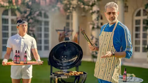 Zeus (Jeff Goldblum) tends a garden barbecue while a server holds a tray