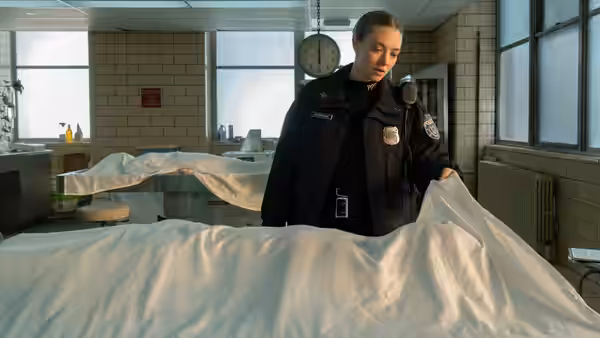 Mickey Fitzpatrick (Amanda Seyfried) lifts a sheet covering a body in the morgue