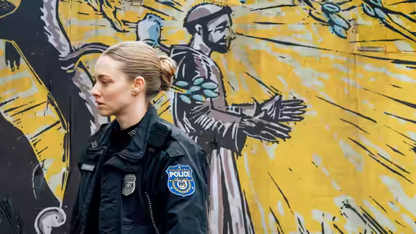 Mickey Fitzpatrick (Amanda Seyfried) walks past a colorful mural in her police uniform