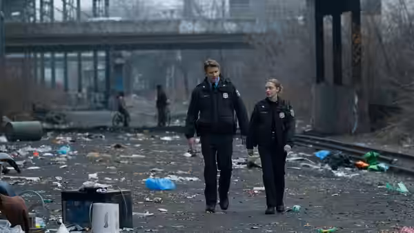 Mickey Fitzpatrick (Amanda Seyfried) and a fellow officer walk through a litter-strewn urban lot