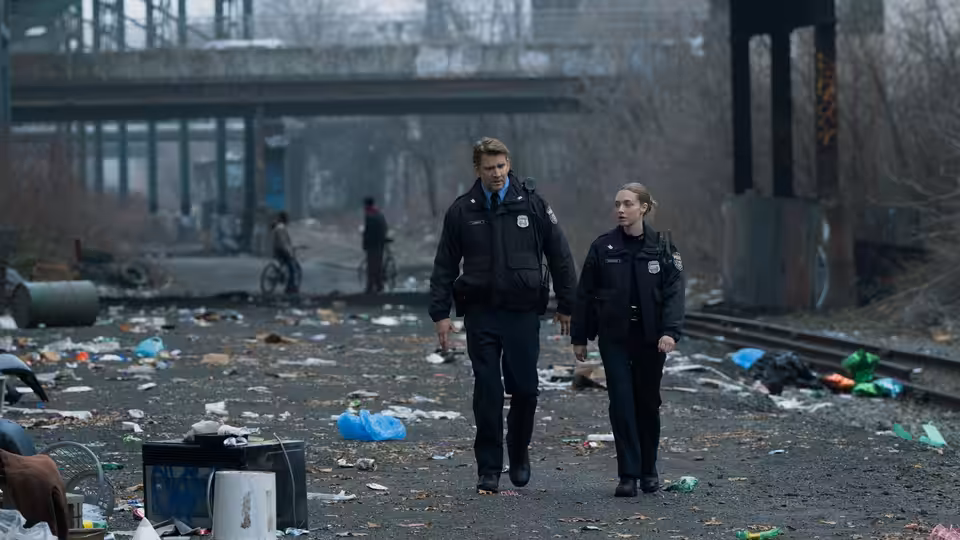 Mickey Fitzpatrick (Amanda Seyfried) and a fellow officer walk through a litter-strewn urban lot