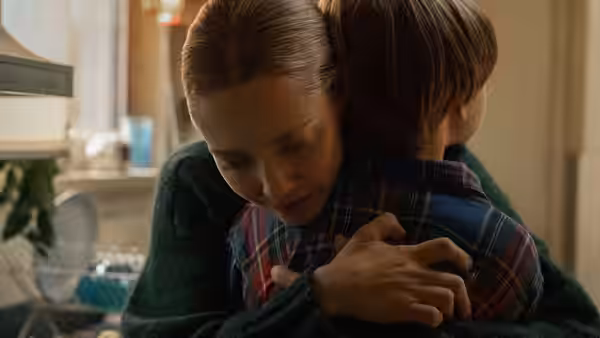 Mickey Fitzpatrick (Amanda Seyfried) embraces a young boy in a kitchen