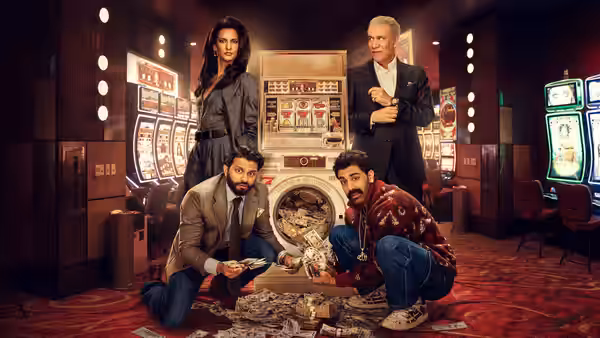 Two men kneel over scattered cash in a casino as a woman and older man stand behind them
