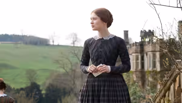 Jane Eyre (Mia Wasikowska) stands outside Thornfield Hall, holding a folded letter