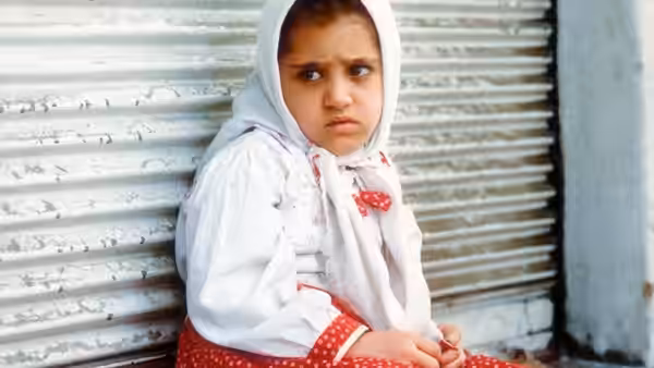 Razieh (Aida Mohammadkhani) sits against a metal shutter, looking to the side
