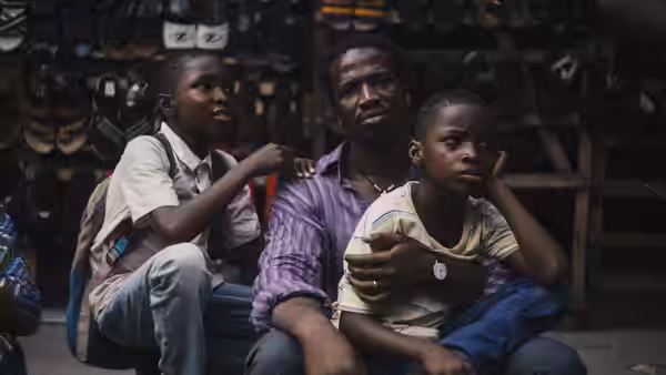 A man sits with two boys inside a shoe shop one on his lap