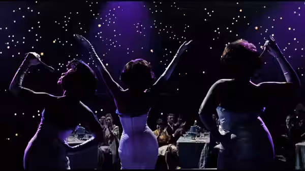 The Dreamettes raise their arms onstage before a seated audience