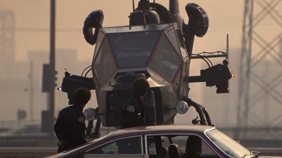Men gather beside the Blue Thunder helicopter behind a car in an urban lot