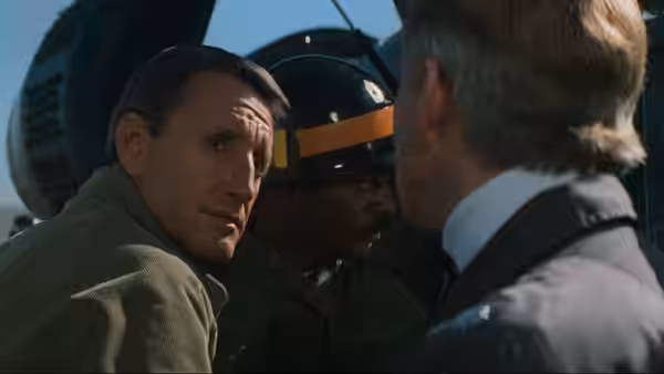 Murphy (Roy Scheider) speaks with a uniformed crewman beside the helicopter